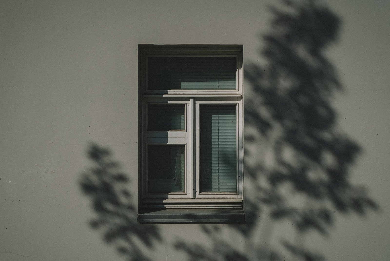 Hand prüft Luftzug an einem geschlossenen Fenster